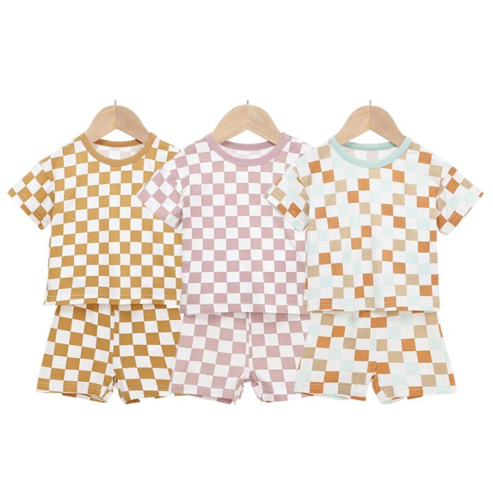 Three checkered bamboo baby pajama sets in mustard pink and orange colorways
