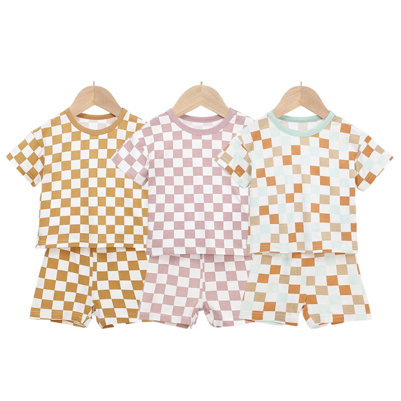 Three checkered bamboo baby pajama sets in mustard pink and orange colorways
