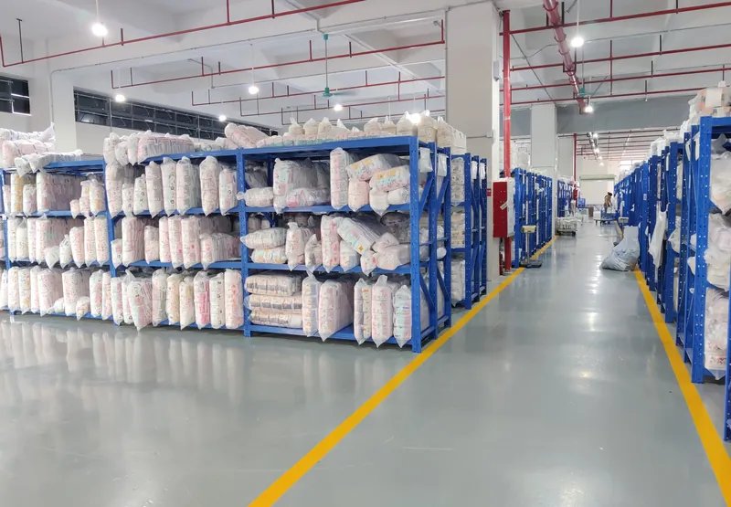 Bagged finished kidswear garments on blue warehouse racks along a dispatch aisle