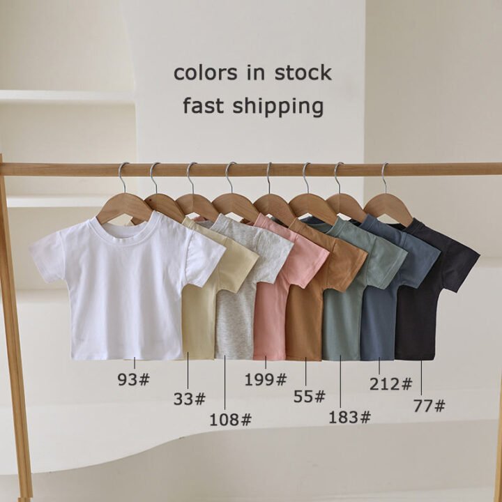 Organic cotton baby T-shirts displayed in eight in-stock colors on wooden hangers
